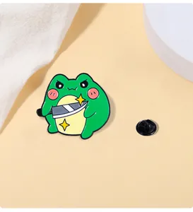 Macro shot of cartoon green frog enamel pin holding a silver knife with back pin clasp
