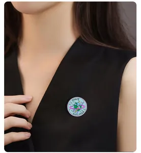 Detailed close-up of a blue enamel earth pin badge on a black V-neck shirt