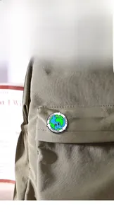 Close-up of enamel earth pins with eco slogans on a khaki canvas backpack