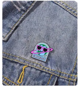 Detail of cartoon earth enamel pin with pink sunglasses and Universe text on denim