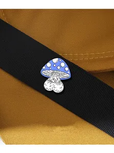 Detail of blue mushroom enamel pin with white dots pinned on brown canvas bag texture