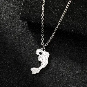 Macro detail of white enamel fish pendant with silver scales on a black textured background