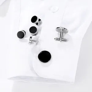 Formal round black cufflinks and studs set displayed on a white shirt cuff for men