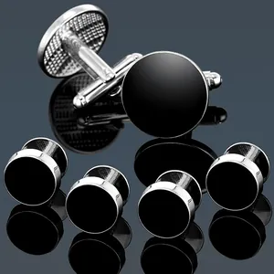 Macro detail of silver round cufflinks set with black enamel inlay on reflective background