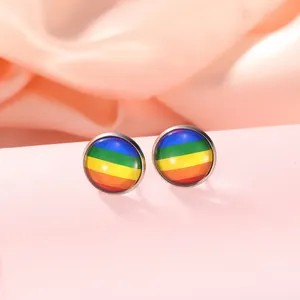 Gros plan de boucles d'oreilles cœur arc-en-ciel sur un fond en velours rose doux