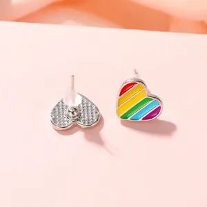 Détail macro de boucles d'oreilles cœur en émail arc-en-ciel avec fermoirs en silicone