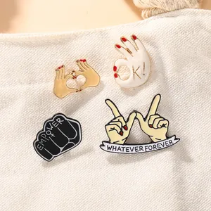 Detailed close-up of four fashion enamel pins with OK and Whatever Forever gestures