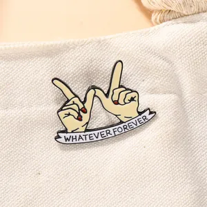 Close-up of Whatever Forever enamel pin with hand gestures on white canvas fabric