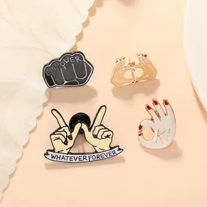 Set of four creative enamel hand gesture pins with Empower and Whatever Forever slogans