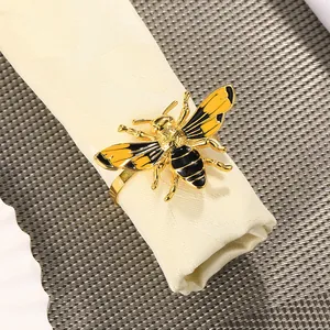 Detalle de servilletero abeja dorada con esmalte sobre servilleta blanca fina