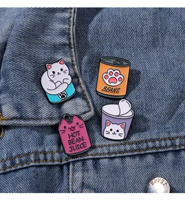 Détail de quatre épingles en émail de chat colorées sur une texture en denim bleu
