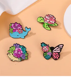 Close-up of animal enamel pins featuring a whale, turtle, hedgehog and butterfly with succulents