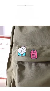 Vue détaillée de pin's chat en émail sur sac en toile verte montrant les détails laqués