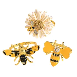 Tres creativos servilleteros de aleación dorada con diseños de abeja y margarita