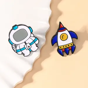 Detail of cartoon enamel pins featuring a white astronaut and a colorful rocket ship