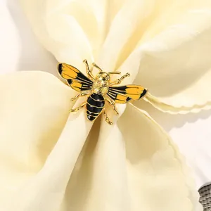 Elegante servilletero de abeja dorada con alas esmaltadas sobre tela blanca