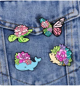 Detail view of four enamel animal pins with succulent motifs on blue denim fabric