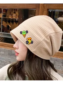 Détail d'un bonnet en maille côtelée beige avec écussons de pizza et crème glacée