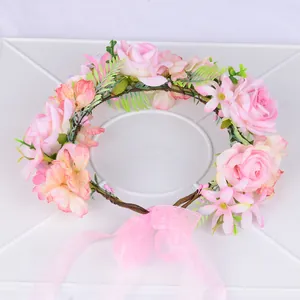 Détail d'une couronne de fleurs roses avec ruban en organza et feuilles vertes