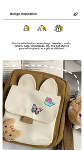 Detailed view of colorful butterfly and blue whale enamel pins on a beige canvas bag
