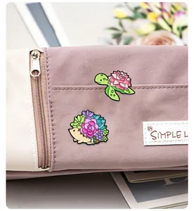 Detail of colorful enamel pins featuring a turtle and hedgehog on a purple canvas bag