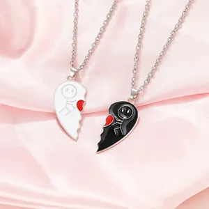 Close-up of interlocking black and white heart pendants with stickman design on pink silk