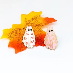 Detail view of ghost enamel pins with floral patterns on a festive orange autumn leaf