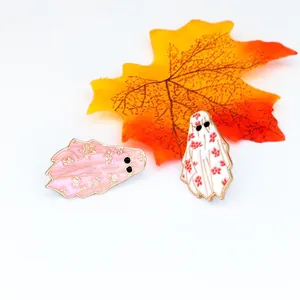 Ghost lapel pin set with pink and white floral patterns on a white background with autumn leaves