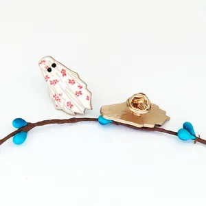 Macro detail of ghost enamel brooch with floral pattern and gold metal butterfly clutch