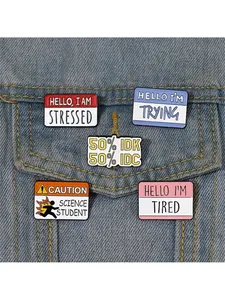 Close-up of five enamel pins with funny English slogans on a light blue denim jacket
