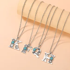 Detail of vintage bohemian initial pendants K, F, Q, H with turquoise and western motifs