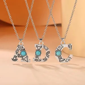 Detail of vintage bohemian initial necklaces with turquoise and western relief patterns