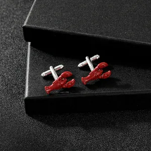 Macro view of vivid red lobster cufflinks paired with silver metal stems on black texture