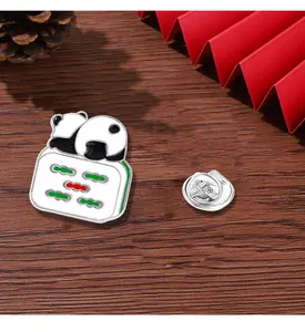 Close-up of enamel panda mahjong pin with metal butterfly clasp on rustic wooden surface