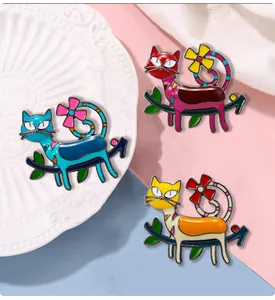 Close-up of three colorful cat enamel pins on tree branches with delicate floral details