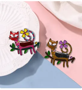 Detailed close-up of vibrant enamel cat brooches with colorful floral accents on a ceramic plate