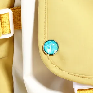 Détail du sac en toile jaune avec une silhouette d'élan blanc sur bouton métallique
