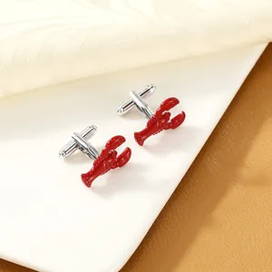 Detail view of red lobster cufflinks with silver base on a ceramic tray
