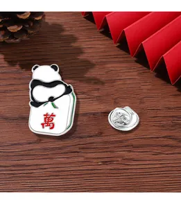 Detail view of panda enamel pin with mahjong tile on a rustic wooden table background