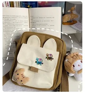 Close-up of canvas crossbody bag with cute cat badges and soft paw pendant detail
