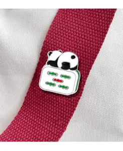 Macro detail of enamel panda pin on mahjong tile with red textured ribbon and canvas background