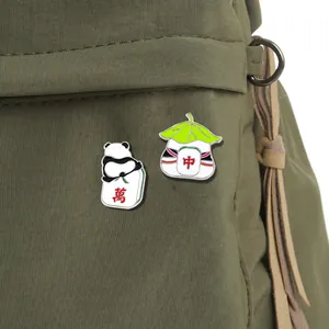 Cute panda and dumpling mahjong enamel pins on an olive green canvas bag