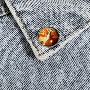 Gros plan d'une broche ronde en métal avec silhouette de renne sur tissu en jean
