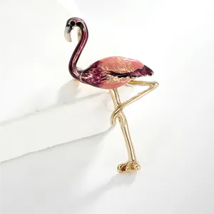 Détail d'une broche flamant rose en émail avec des bords dorés et un fini dégradé élégant