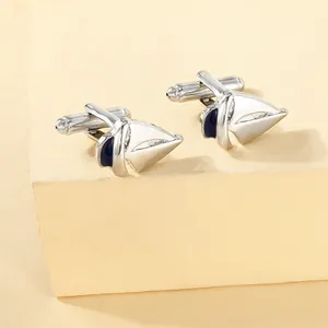Macro view of sailboat cufflinks with white enamel and polished silver metal details