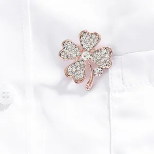 Nahaufnahme der roségoldenen Kleeblatt-Brosche mit Diamanten auf einem weißen Hemd
