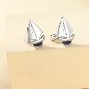 Close-up of nautical white sailboat cufflinks with navy blue enamel inlay on stone