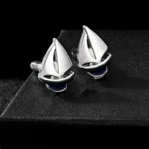 Detailed view of silver nautical sailboat cufflinks with blue enamel on a black texture box