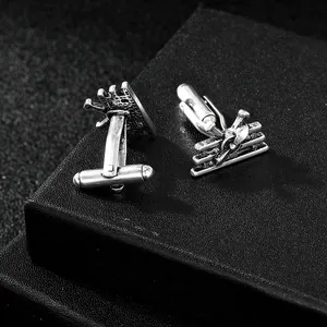 Macro shot of vintage silver biplane cufflinks with detailed wings on black leather background