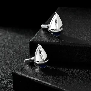 Macro view of sailboat cufflinks with white and blue enamel on black textured box